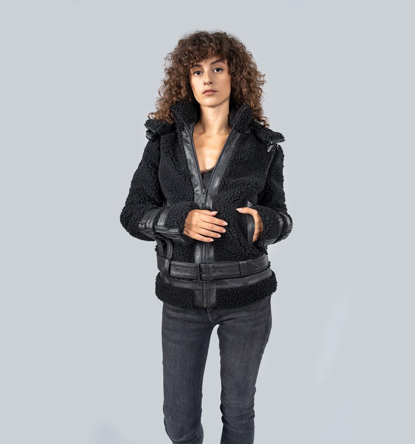 Mädchen mit lockigem braunem Haar in schwarzer Lederjacke mit Kragen, frontal posierend