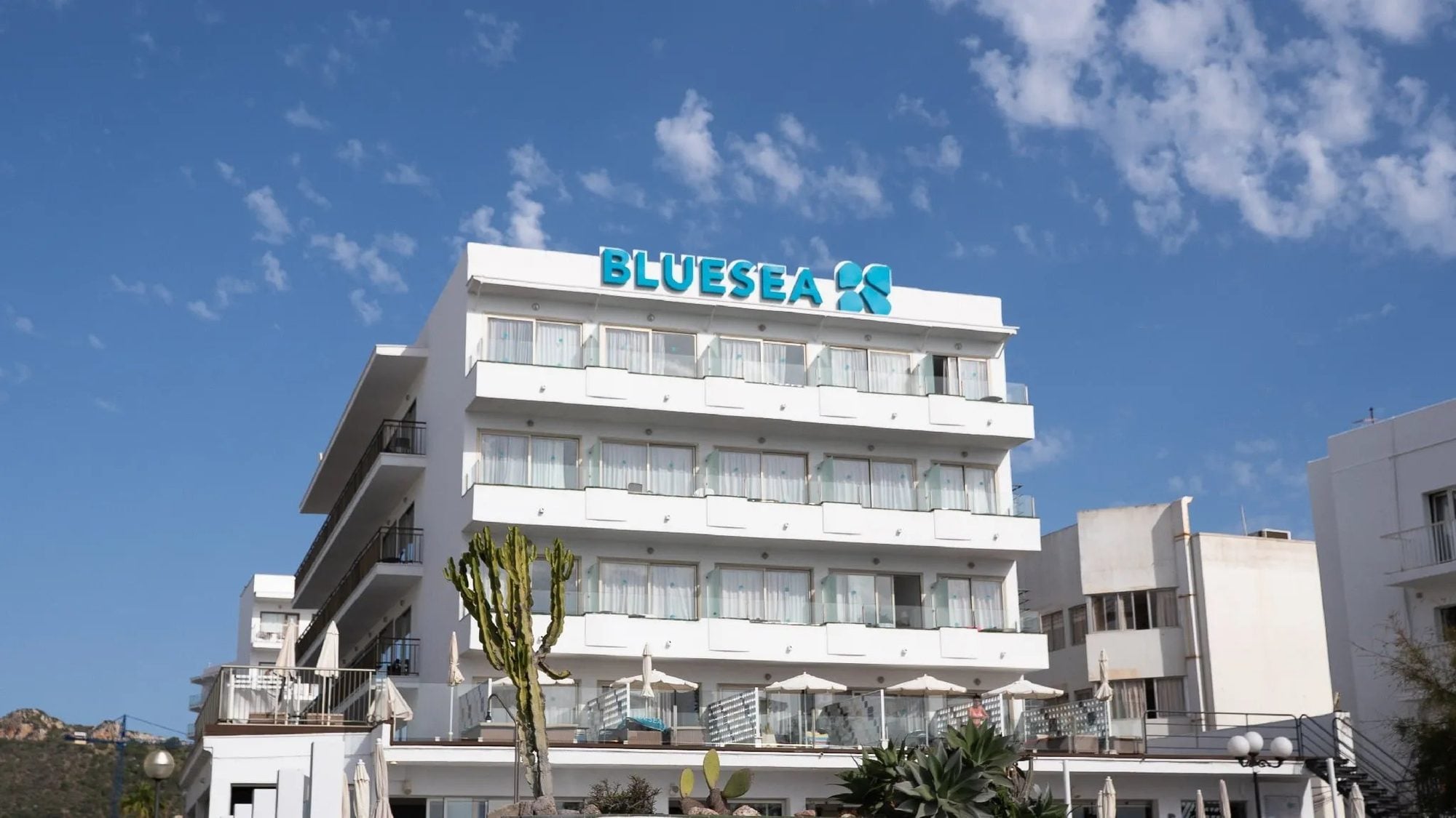 Fachada blanca del hotel con letrero azul turquesa en la azotea