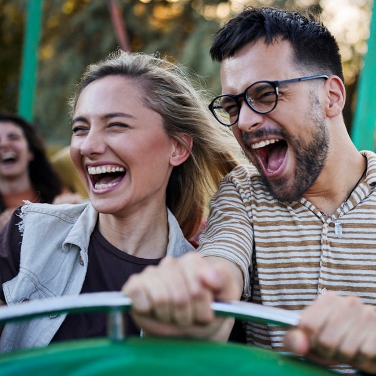 Pareja joven riendo mientras juegan en una atracción verde al aire libre