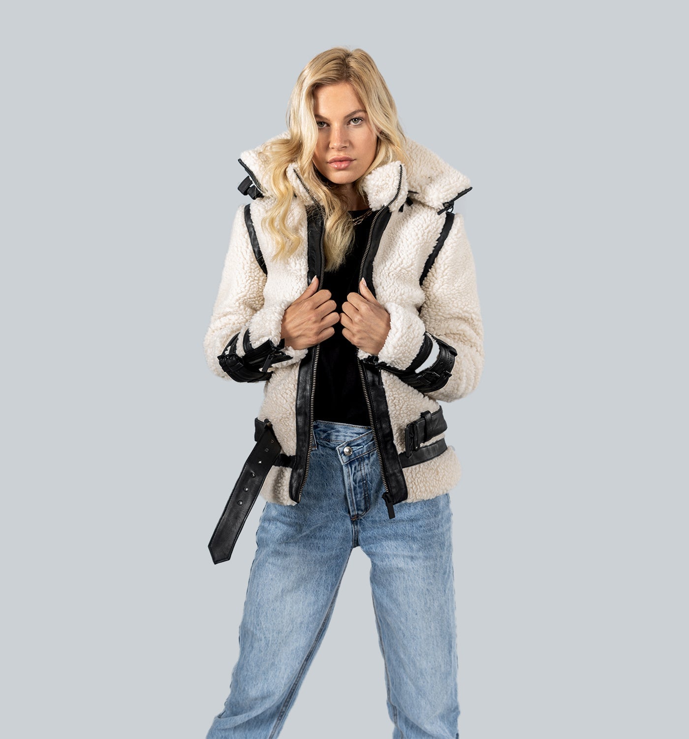 Blonde Frau in Creme-Fleece-Jacke mit schwarzen Ledereinsätzen und heller Jeans