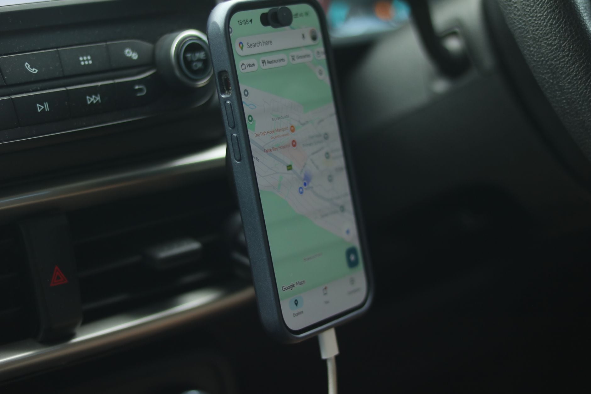 Smartphone med navigationskarta monterad i bilens instrumentbräda visar sökfunktion och restaurangöversikt